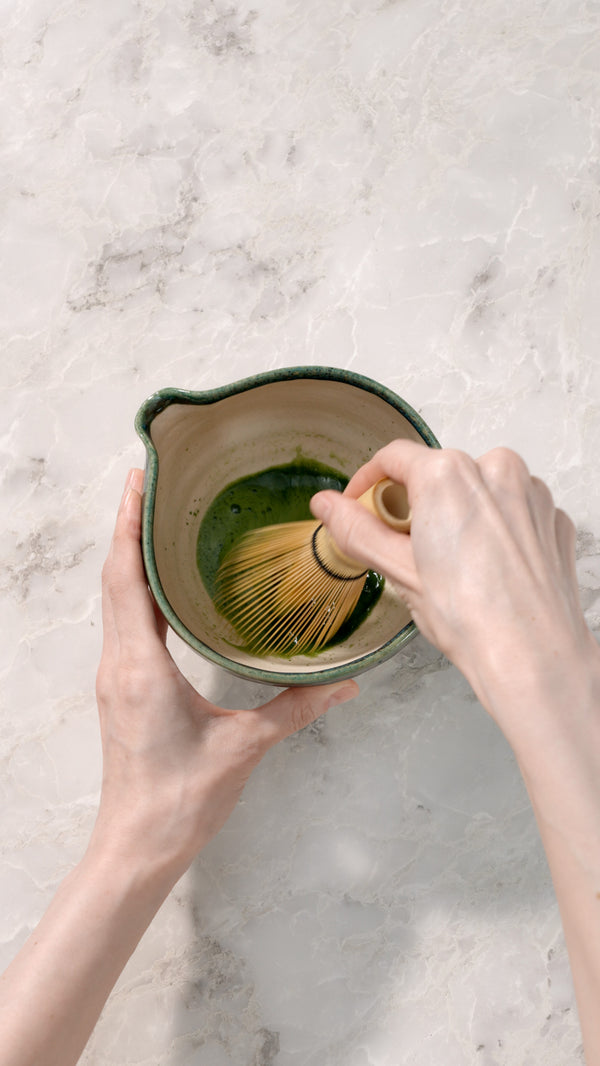 Whisking matcha with a bamboo whisk