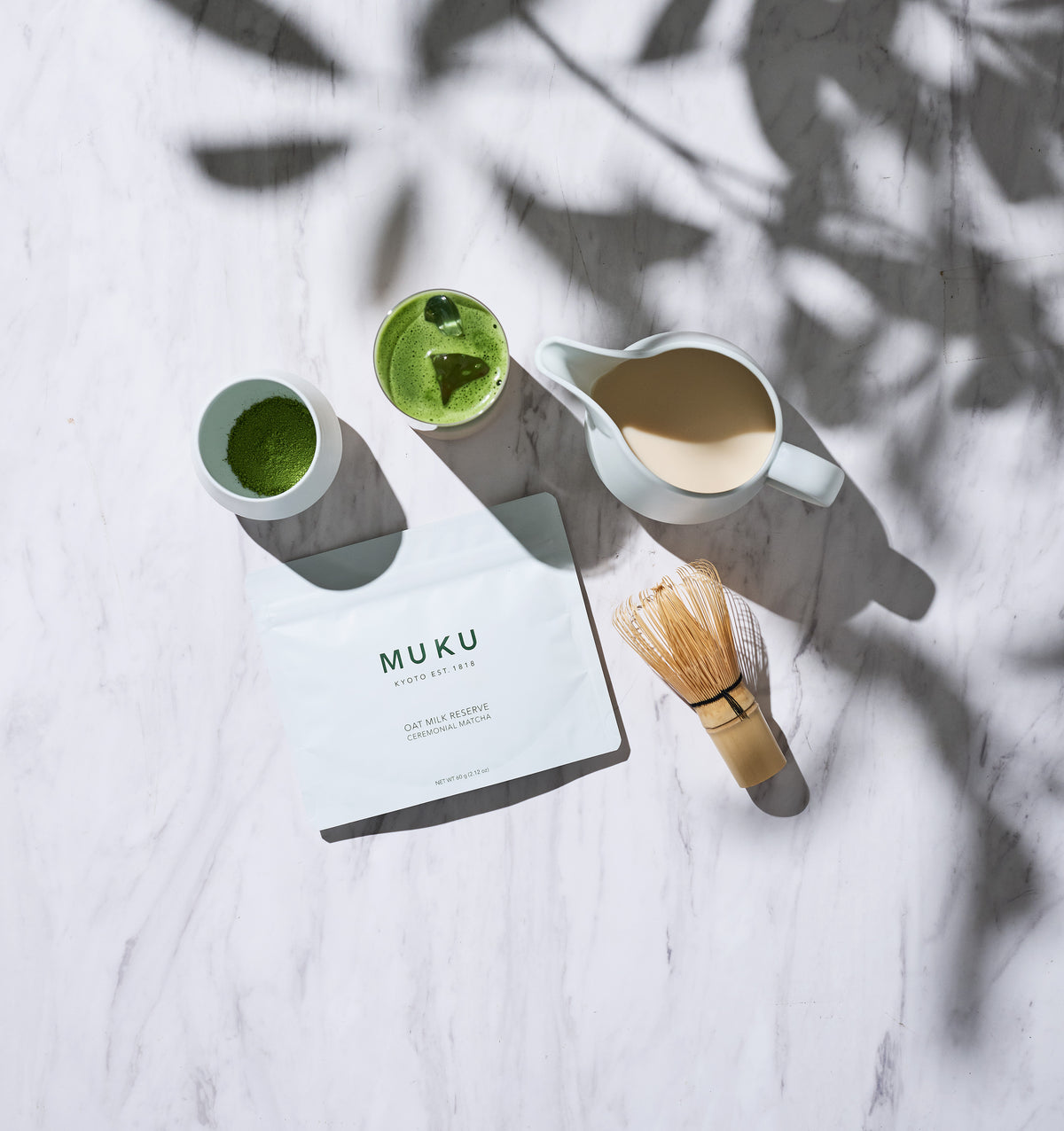 MUKU Oat Milk Reserve 60g pouch with matcha, oat milk and a bamboo whisk