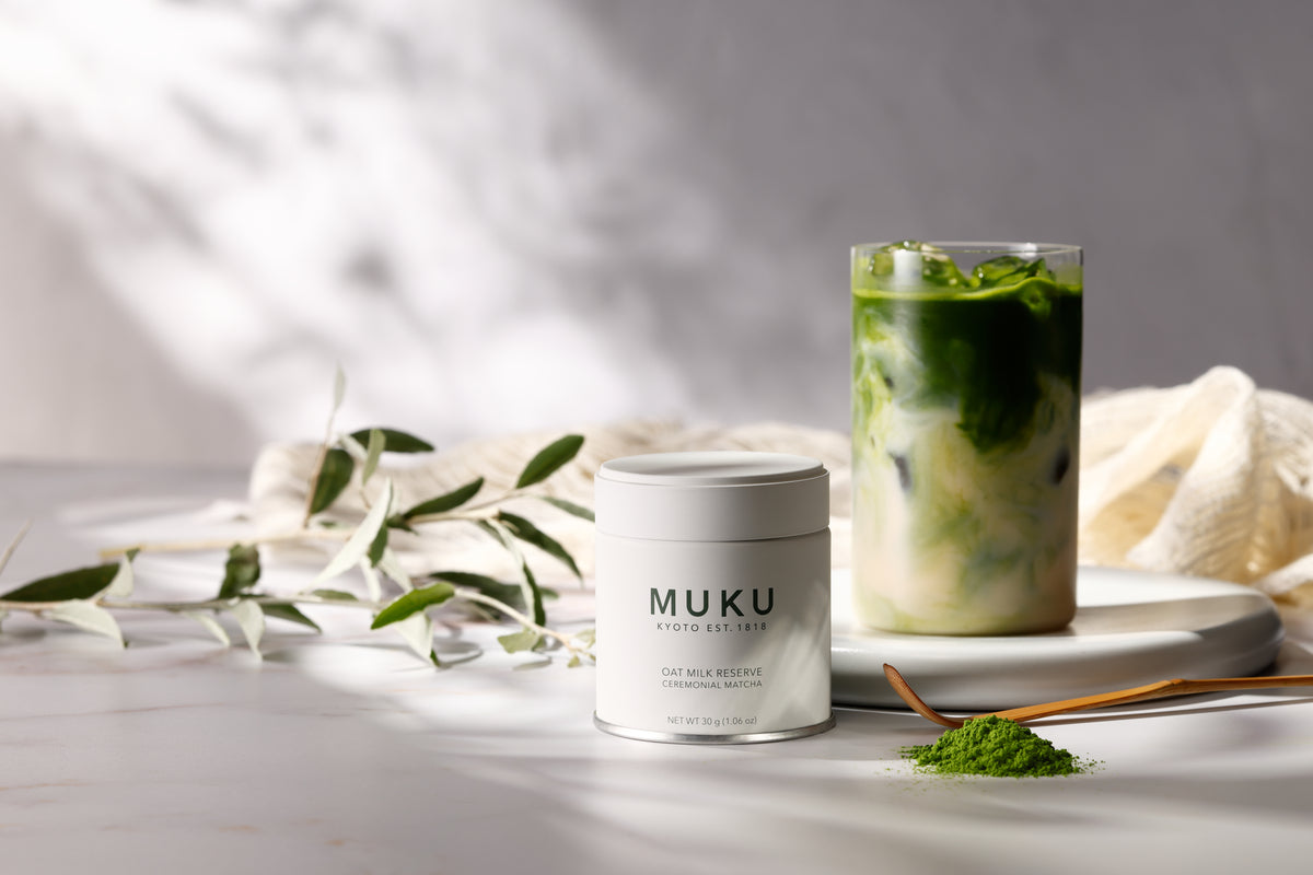 MUKU Oat Milk Reserve 30g tin beside an oat milk matcha latte and a linen cloth